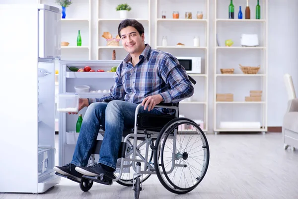 Young disabled injured man opening the fridge door — Stock Photo, Image