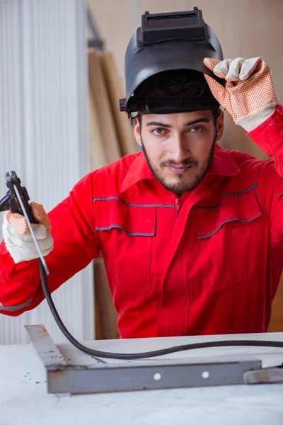 Jeune réparateur avec une électrode de pistolet à souder et un casque de soudage — Photo