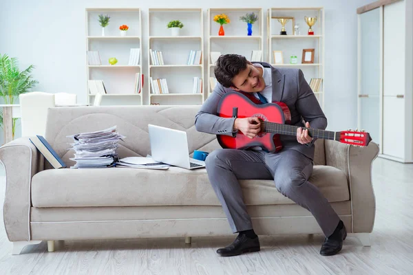 Evde gitar çalan bir iş adamı.
