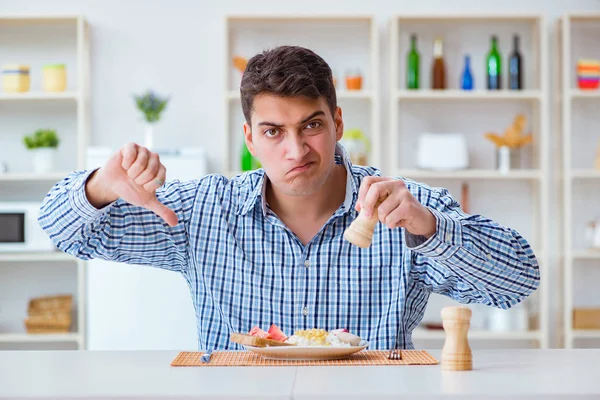 Młody mąż jedzący niesmaczne jedzenie w domu na lunch — Zdjęcie stockowe