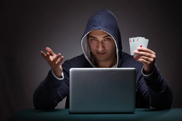 Jovem usando um capuz sentado na frente de um computador portátil — Fotografia de Stock