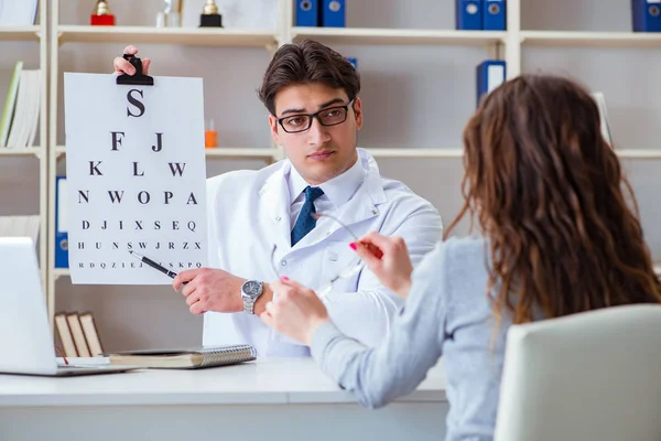 Doctor optician with letter chart conducting an eye test check — Stock Photo, Image