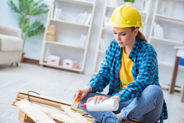 Tamirci kadın marangoz ahşap döşemeleri kesiyor.