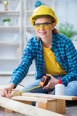 Tamirci kadın marangoz ahşap döşemeleri kesiyor.