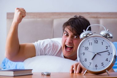 Yataktaki adam alarm yüzünden uykusuzluk çekiyor.