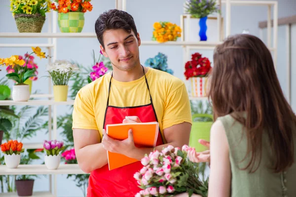 Çiçekçi dükkanında çiçek satıyor.