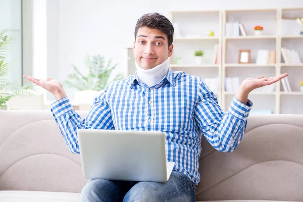 Man freelancer in a cervical collar neck brace working from home — Stock Photo, Image