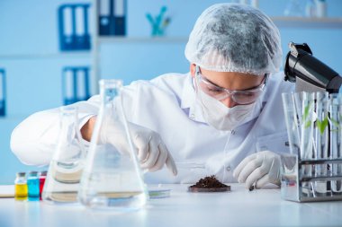 Erkek bilim adamı bir laboratuarda deney yapıyor.