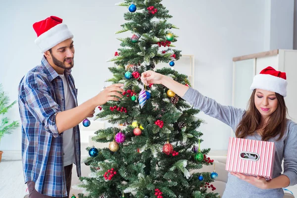 Genç aile Noel ağacını mutlu bir vesileyle süslüyor.