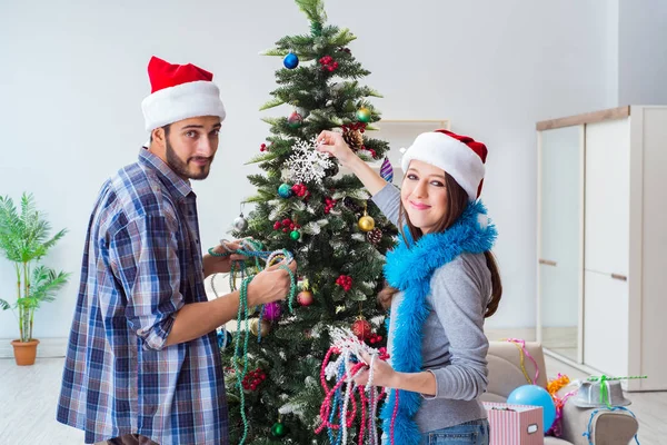 Genç aile Noel ağacını mutlu bir vesileyle süslüyor.