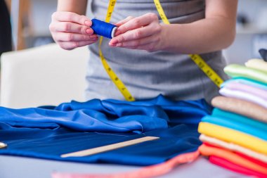 Kadın terzi dikiş dikmek için dikiş dikiyor.