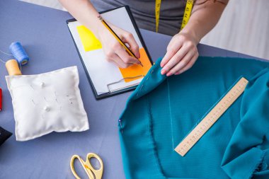 Kadın terzi dikiş dikmek için dikiş dikiyor.