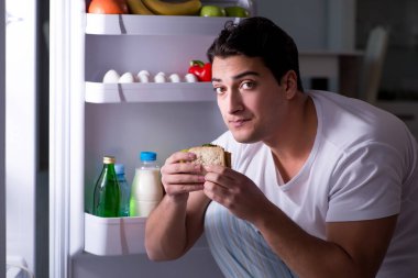 Buzdolabındaki adam gece yemek yiyor.