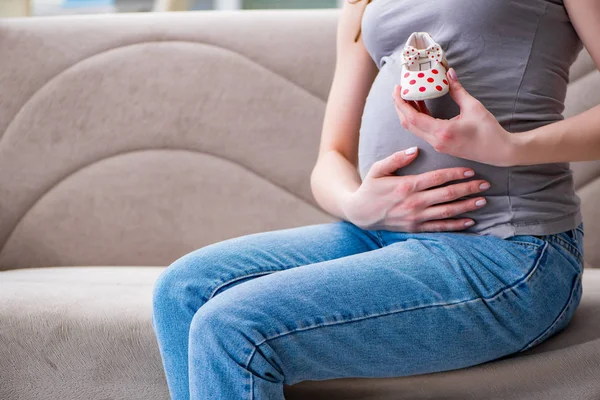 Femme enceinte avec un ventre assis sur un canapé à la maison — Photo