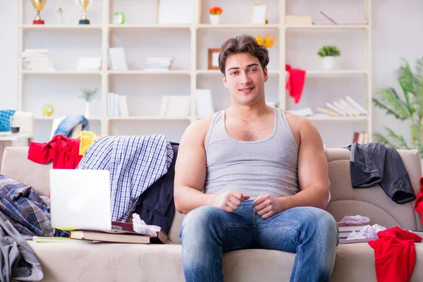 Genç adam dağınık bir odada çalışıyor.