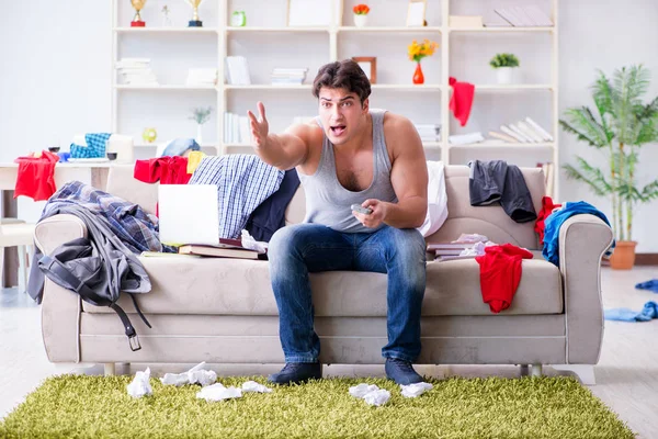 Joven trabajando estudiando en una habitación desordenada — Foto de Stock