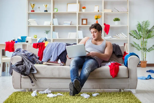 Genç adam dağınık bir odada çalışıyor.