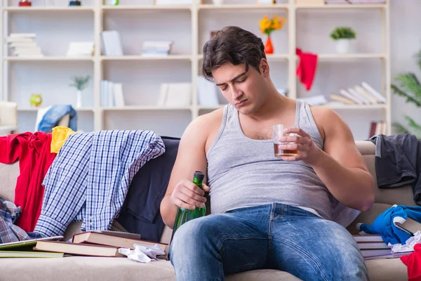 Dağınık bir odada alkol alan genç bir öğrenci.