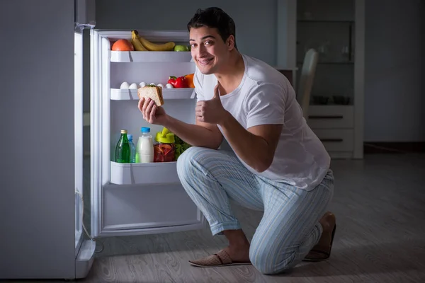 晚上在冰箱边吃饭的男人 — 图库照片