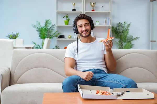 Pizza yiyen adam evde yemek yiyor, dinleniyor.