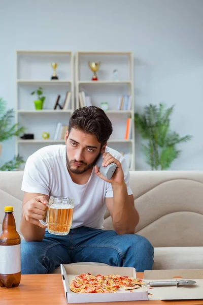 Pizza yiyen adam evde yemek yiyor, dinleniyor.