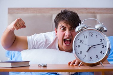 Yataktaki adam alarm yüzünden uykusuzluk çekiyor.