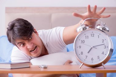 Yataktaki adam alarm yüzünden uykusuzluk çekiyor.