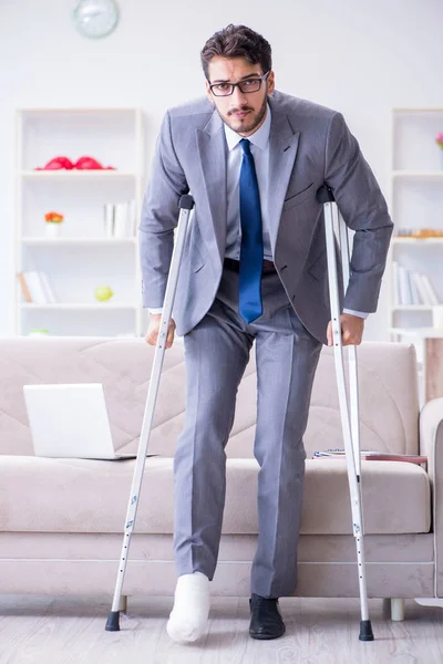 Empresário com muletas e perna quebrada em casa trabalhando — Fotografia de Stock