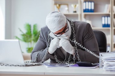 Bandajlı işadamı büroda kağıt işleriyle uğraşıyor.