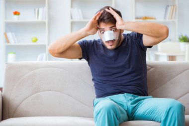 Genç adam estetik cerrahi burnundan sonra evde iyileşiyor.