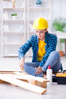 Tamirci kadın marangoz ahşap döşemeleri kesiyor.