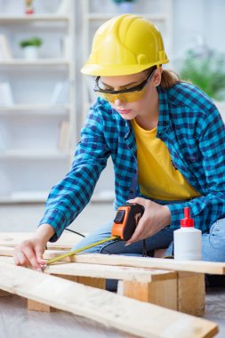 Tamirci kadın marangoz ahşap döşemeleri kesiyor.