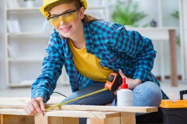 Tamirci kadın marangoz ahşap döşemeleri kesiyor.