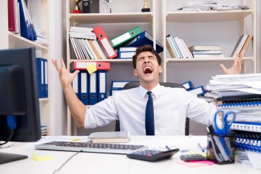 Ofiste kitap ve kağıtlarla çalışan bir işadamı.