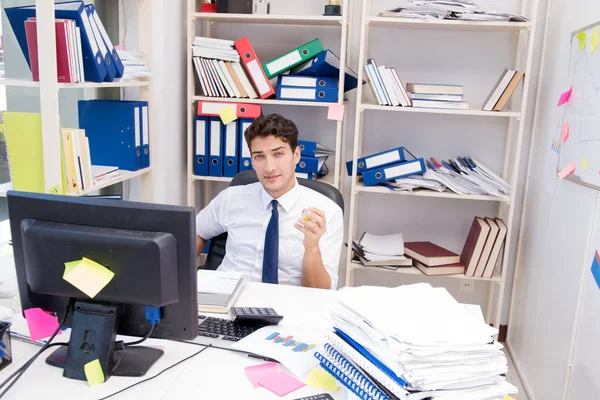 Uomo d'affari che lavora in ufficio con mucchi di libri e carte — Foto Stock