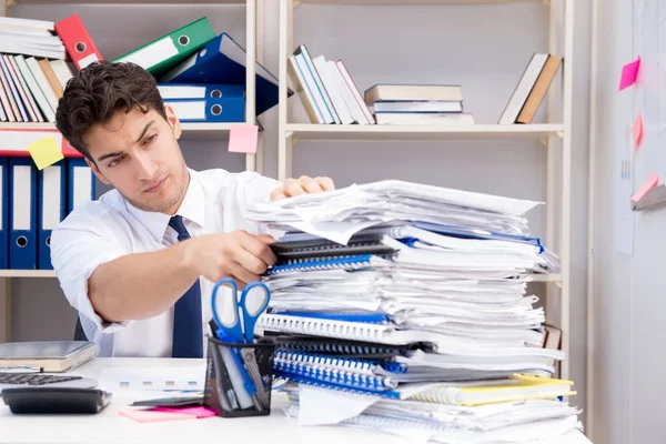 Zakenman werkzaam in het kantoor met stapels boeken en papieren — Stockfoto