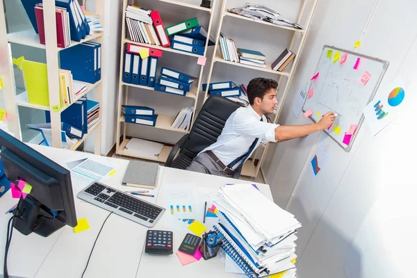 Empresario trabajando en la oficina con montones de libros y papeles —  Fotos de Stock