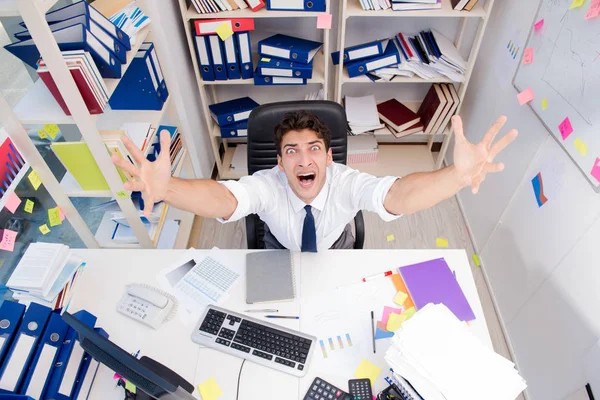 Geschäftsmann arbeitet im Büro mit Stapeln von Büchern und Papieren — Stockfoto