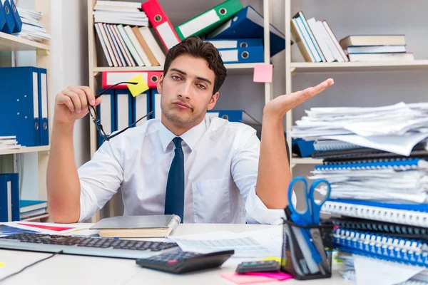 Homme d'affaires travaillant dans le bureau avec des piles de livres et de papiers — Photo