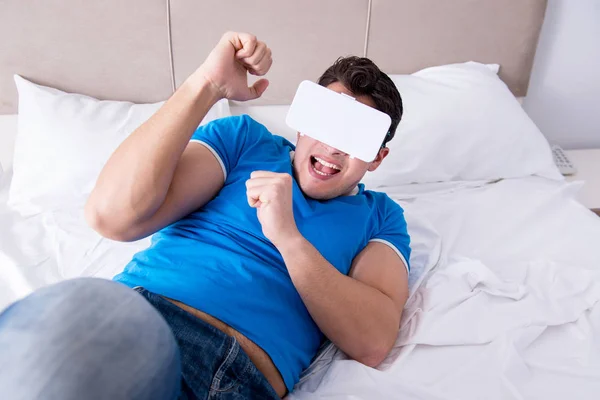 Молодой человек в постели в комплекте виртуальной реальности — стоковое фото