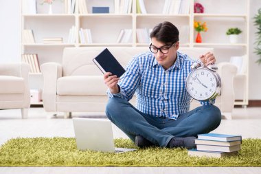 Genç yakışıklı adam evde yerde oturuyor.