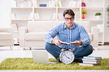 Genç yakışıklı adam evde yerde oturuyor.