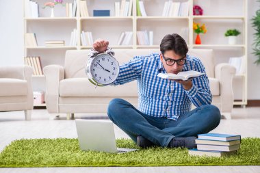 Genç yakışıklı adam evde yerde oturuyor.