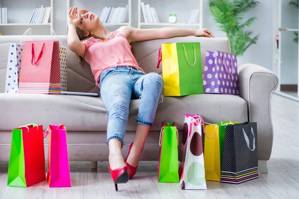 Mujer joven con bolsas de compras en el interior de casa en el sofá —  Fotos de Stock