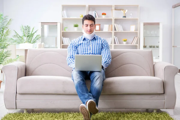 Man freelancer in a cervical collar neck brace working from home — Stock Photo, Image