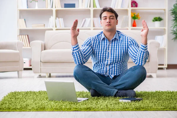 Genç yakışıklı adam evde yerde oturuyor.