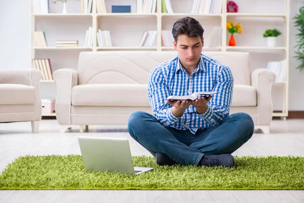 Genç yakışıklı adam evde yerde oturuyor.
