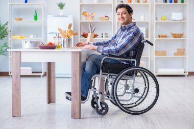 Engelli genç koca mutfakta çalışıyor.