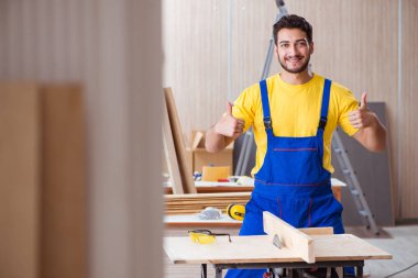 Genç tamirci marangoz odun kesiyor.