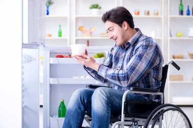 Genç sakat adam buzdolabının kapısını açıyor.